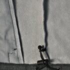 Close-up of a gray fleece jacket with an adjustable drawstring at the bottom hem.