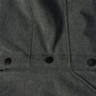Close-up of a gray fabric jacket with black snap buttons and detailed stitching.