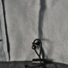 Close-up of a gray fleece jacket hem with a black adjustable drawstring and toggle.