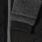 Close-up of a gray sweater sleeve with ribbed cuff next to a silver zipper on a black jacket.