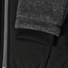 Close-up of a black jacket sleeve with a gray ribbed cuff and a silver zipper.
