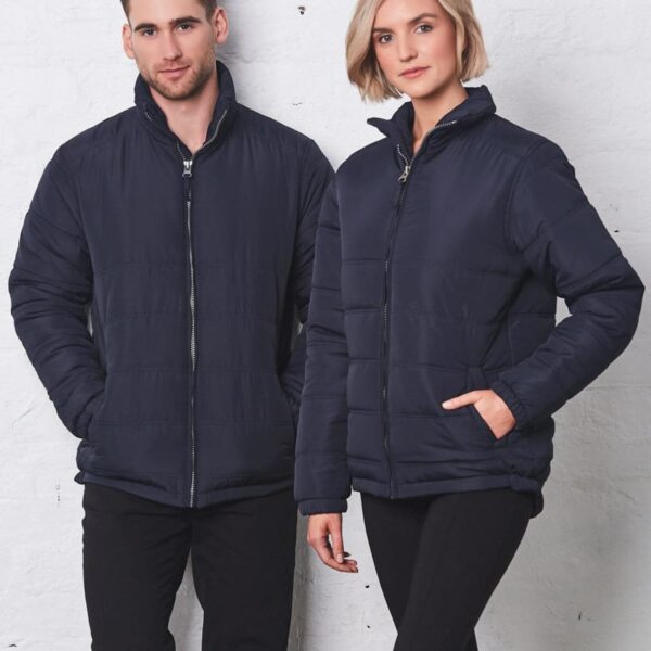 A man and woman wearing matching black puffer jackets and black pants stand side by side.