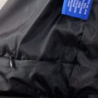 Close-up of a black jacket with a blue care label and a visible zipper pull.