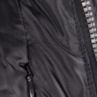 Close-up of a black jacket with a zipper and a small pocket zipper.