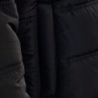 Close-up of a black puffer jacket with visible stitching and a side pocket.