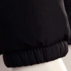 Close-up of a black puffer jacket sleeve with an elastic cuff on a white background.