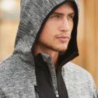 Man wearing a gray hooded jacket looking into the distance.