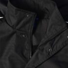 Close-up of a black jacket with a high collar, zipper, and snap button closures.