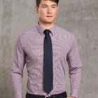 Man in a dress shirt and tie standing against a gray textured background.