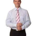 Man in a light blue dress shirt and striped pink tie, standing and smiling at the camera.