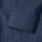 Close-up of a navy blue dress shirt sleeve with a small white dotted pattern.