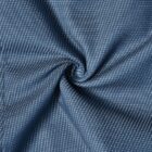 Blue fabric with small white dots, twisted in the center creating folds and texture.