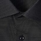 Close-up of a black slim fit shirt with white dotted pattern and a black button.
