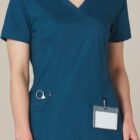 Person wearing blue medical scrubs with scissors in pocket and a blank ID badge clipped on.
