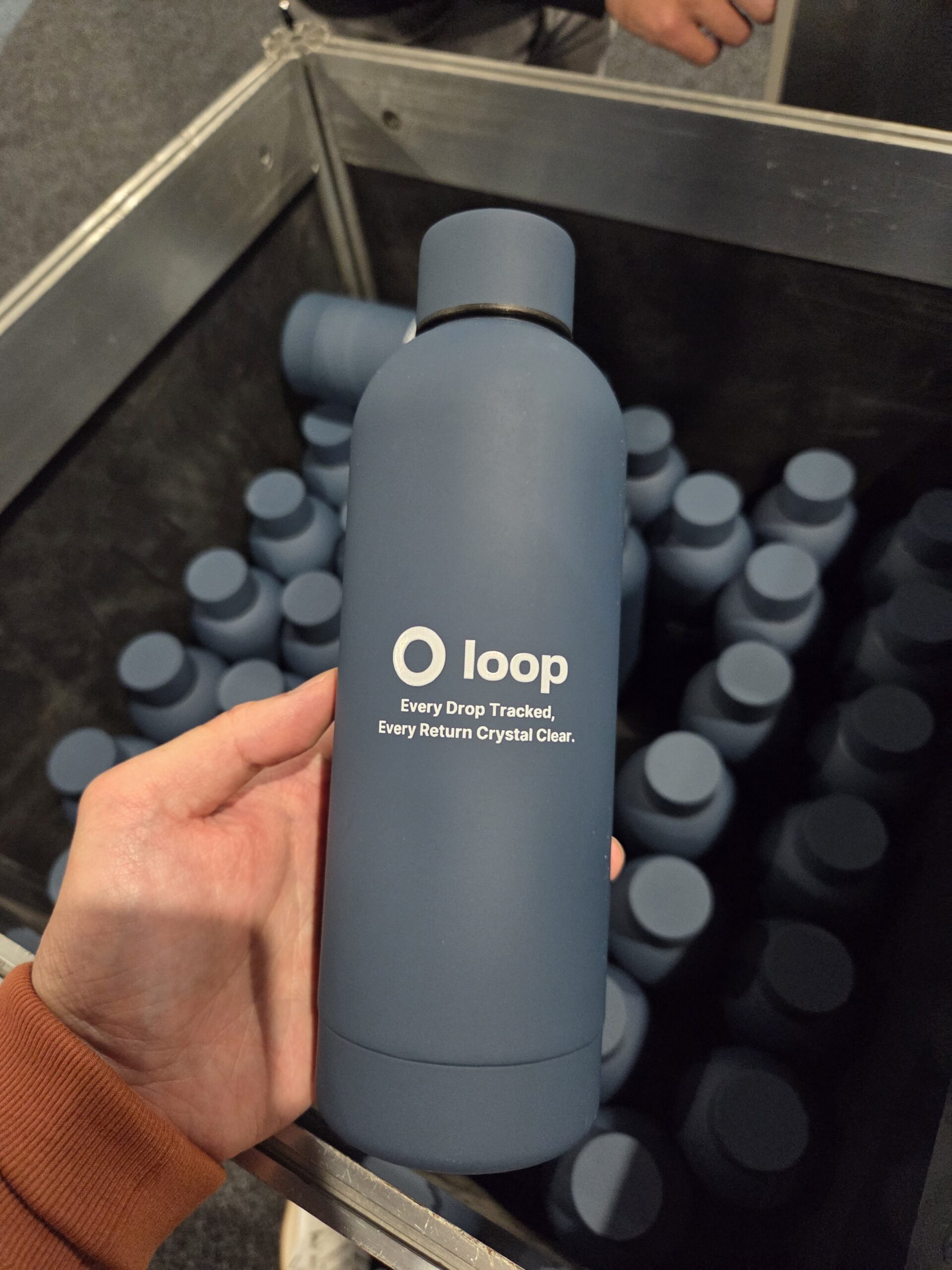 A hand holds a blue Loop bottle above a box at the 2025 Online Retailer Conference Sydney.