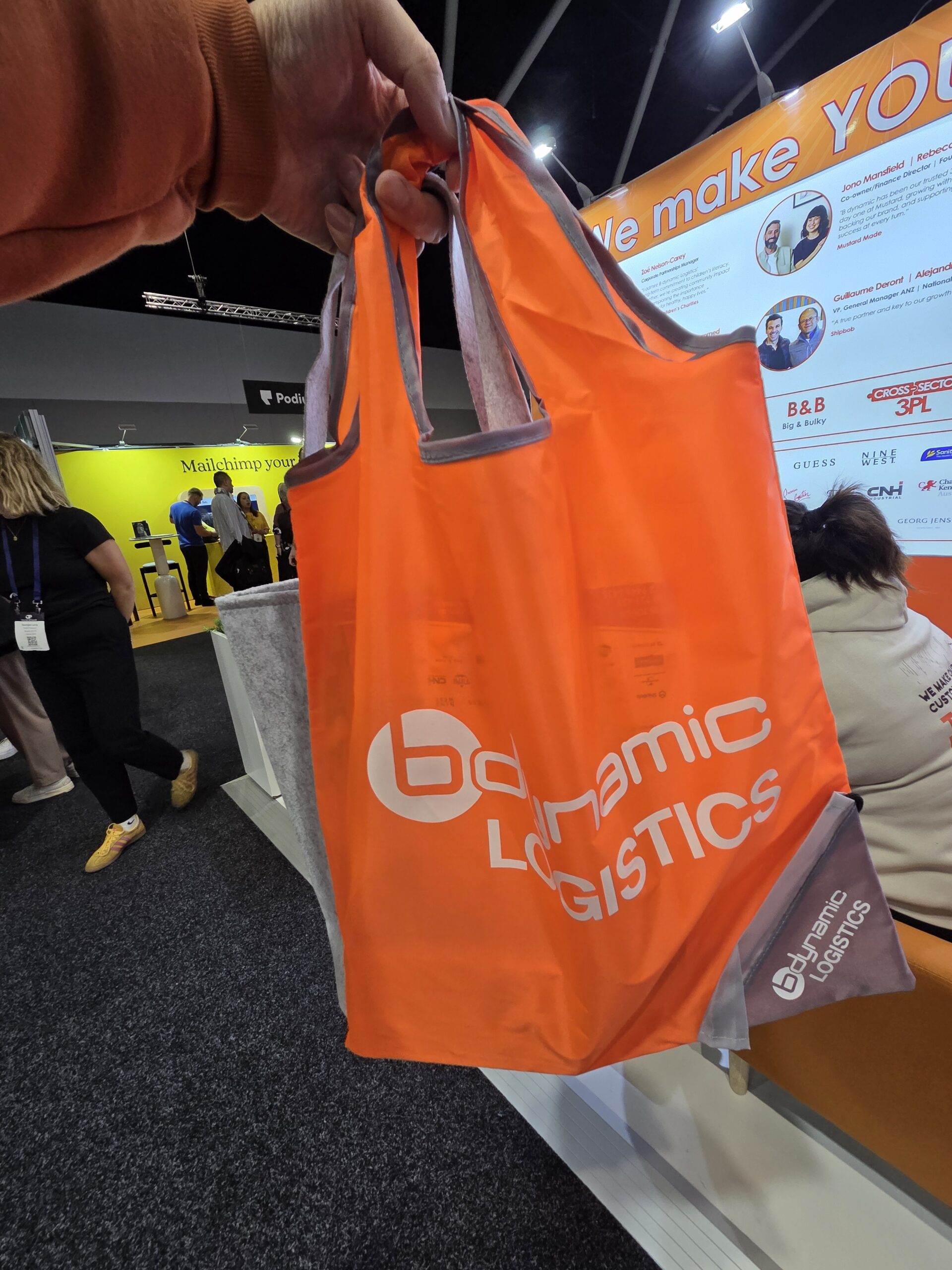 Hand holding a bright orange Dynamic Logistics tote at the 2025 Online Retailer Conference Sydney.