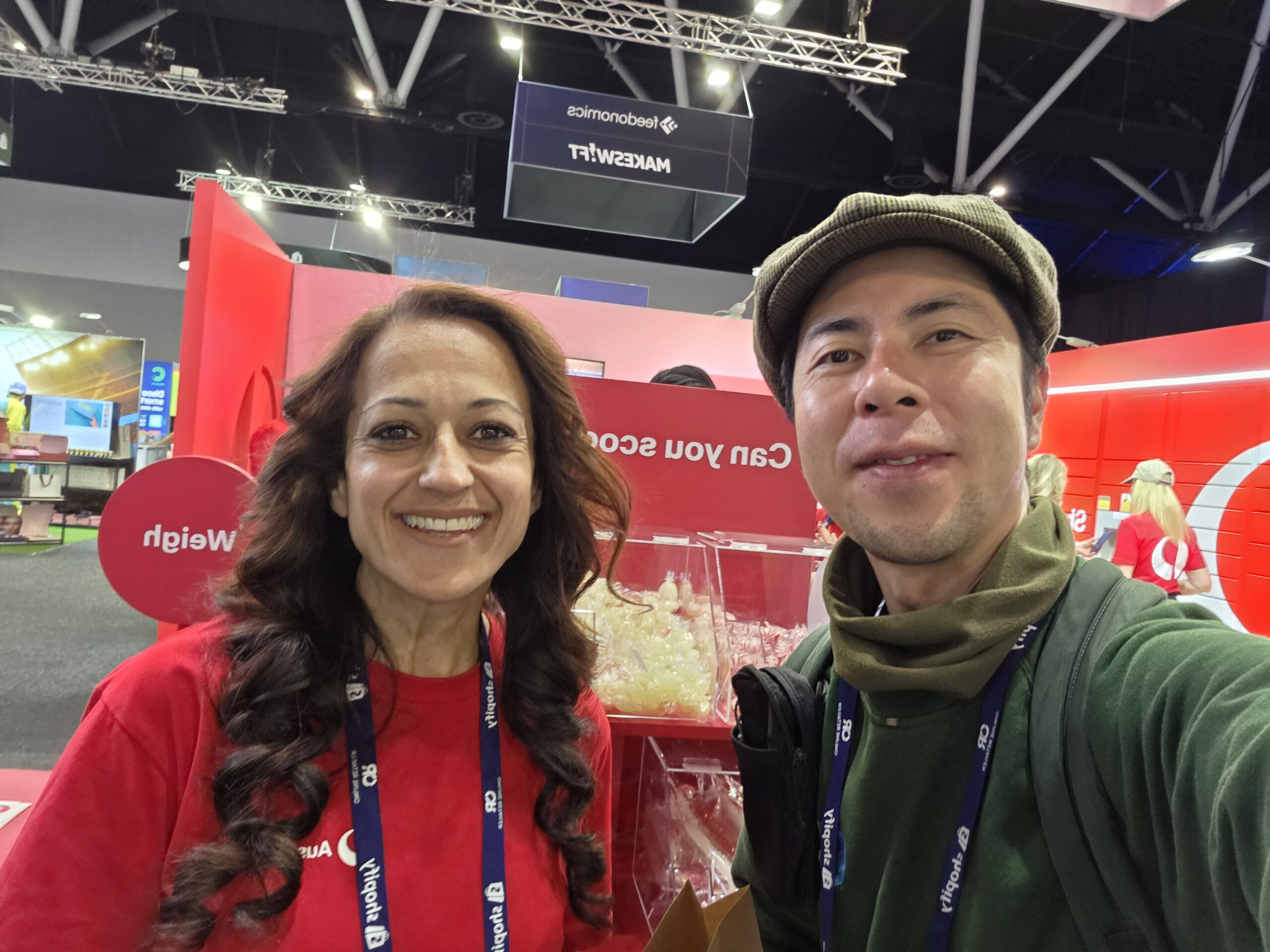 Two people smiling at the 2025 Online Retailer Conference Sydney in front of a bright red booth.