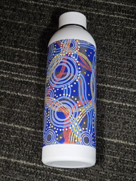 White Custom Bottles with colorful abstract circles, lying on a gray textured carpet.