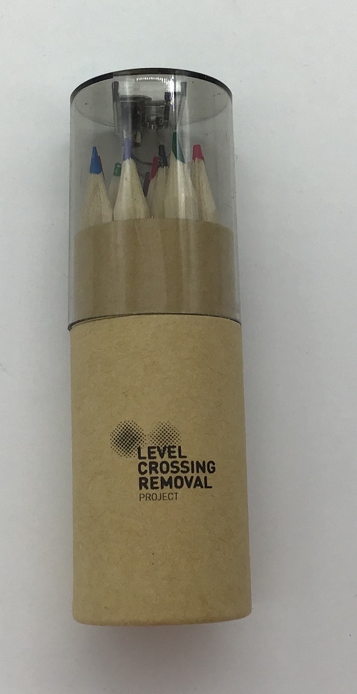 A set of colored pencils in a cardboard tube labeled Level Crossing Removal Project.