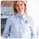 Smiling woman in blue shirt with a logo, standing indoors, focused on business goals.