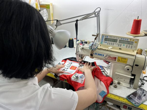 Person sewing a red and white sports jersey