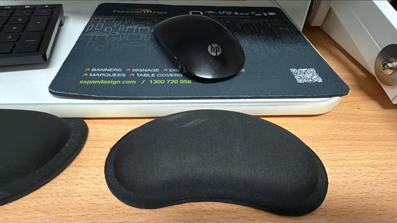 A black HP mouse, a potential merch idea, sits next to a keyboard on a wooden desk.