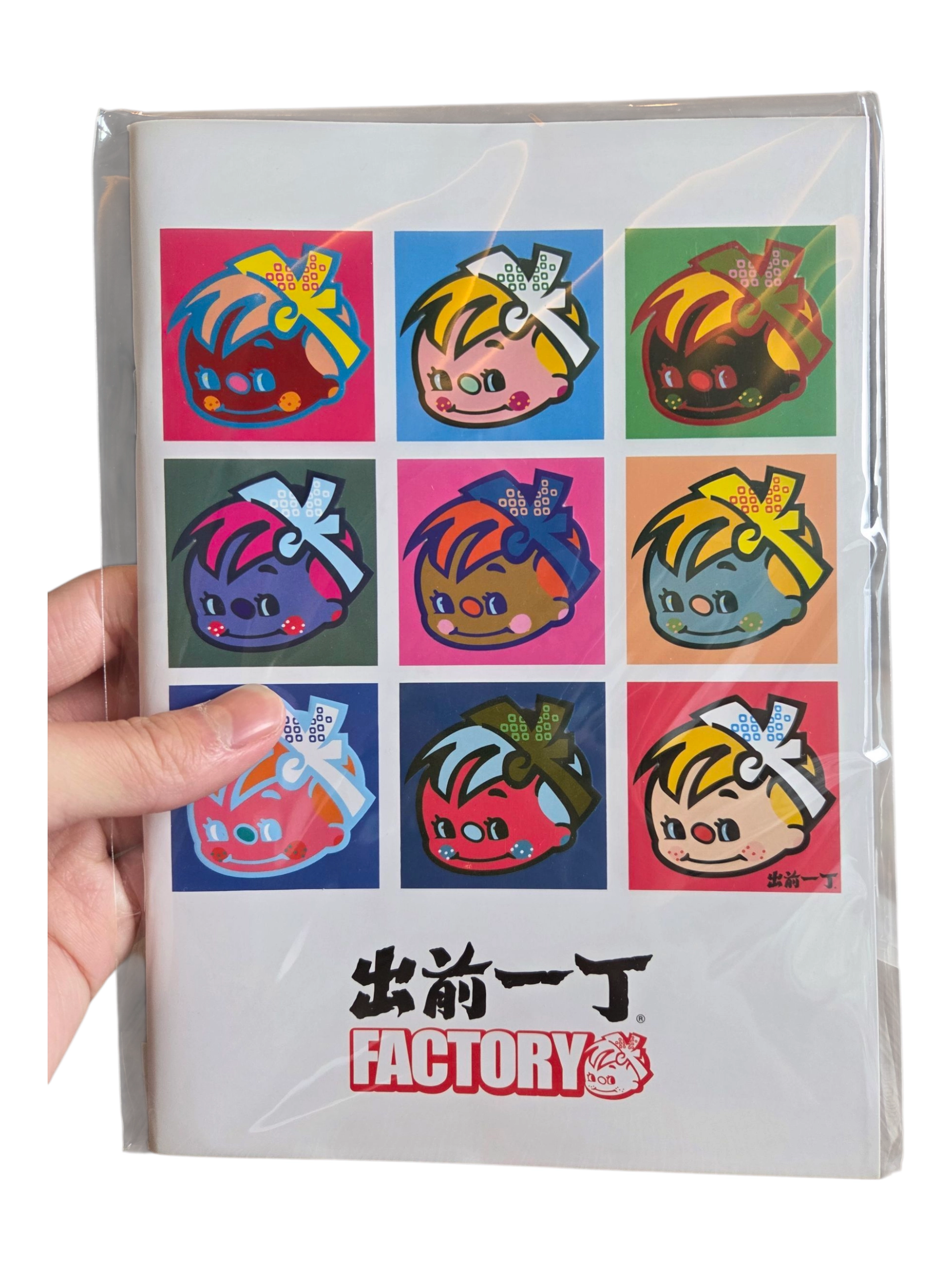 A hand holds custom merchandise: a card with nine colorful cartoon faces in pop art style.