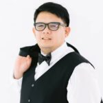 Leo Cruz Man in glasses, tuxedo vest, and bow tie, holding his jacket