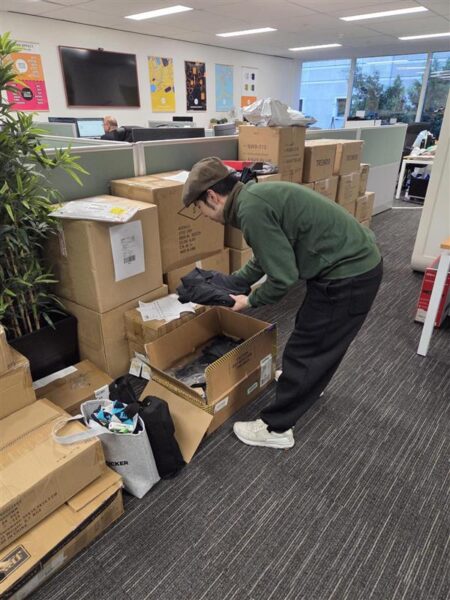 man folding clothes with a box in front of him