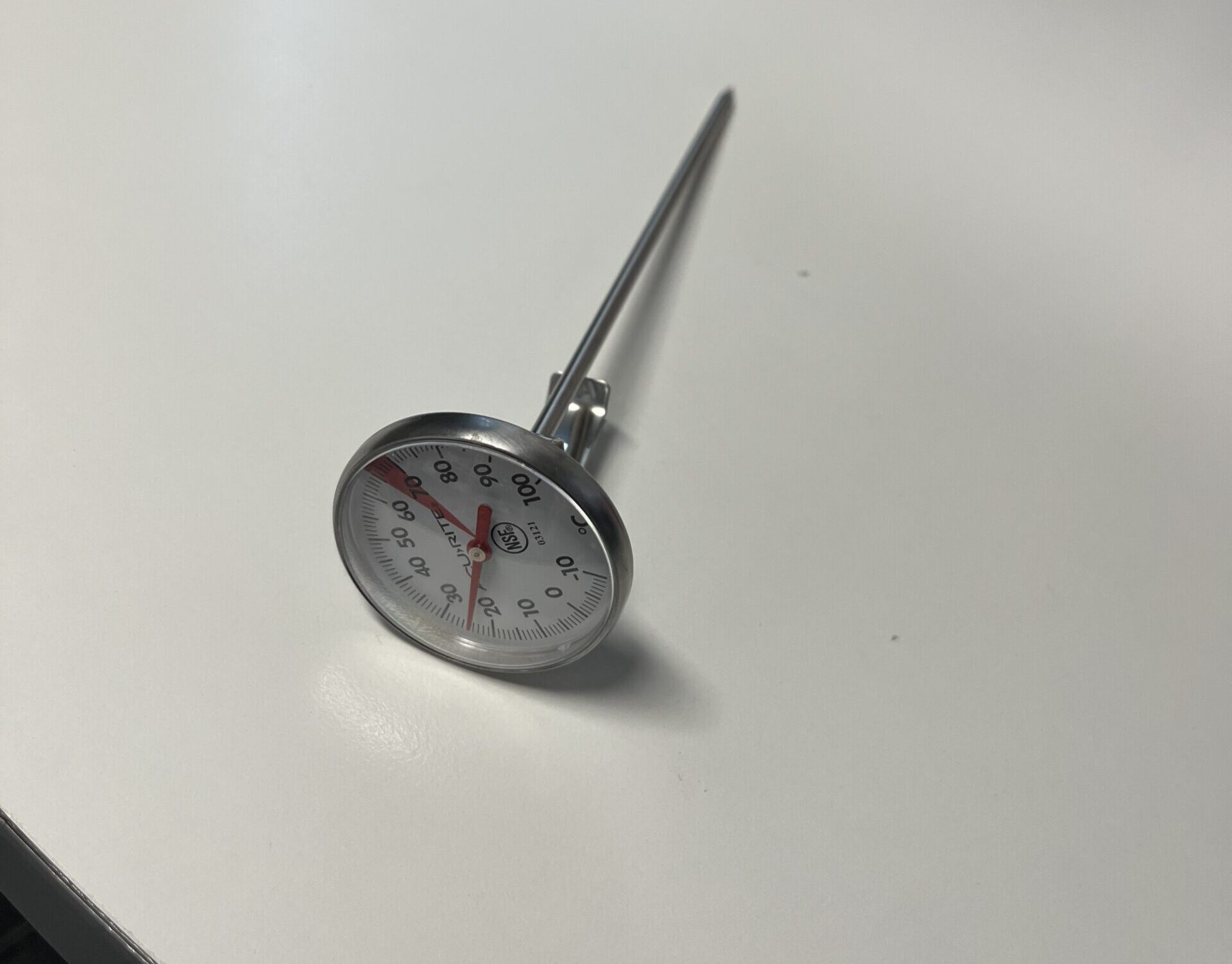 A metal dial thermometer with a probe, perfect for checking heat in thermal cups.