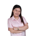 Woman in a pink shirt smiling with arms crossed, perfect for corporate Christmas gifts.