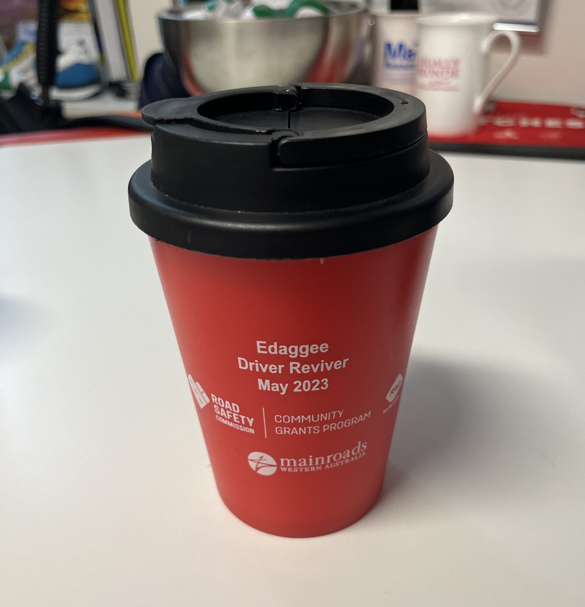 A red thermal cup labeled Edaggee Driver Reviver May 2023