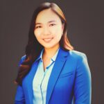 Woman in a blue blazer smiling against a dark background