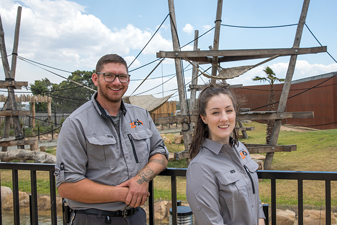 Two zoo staff members smiling in front of a new exhibit at the Zoos’ outdoor enclosure.