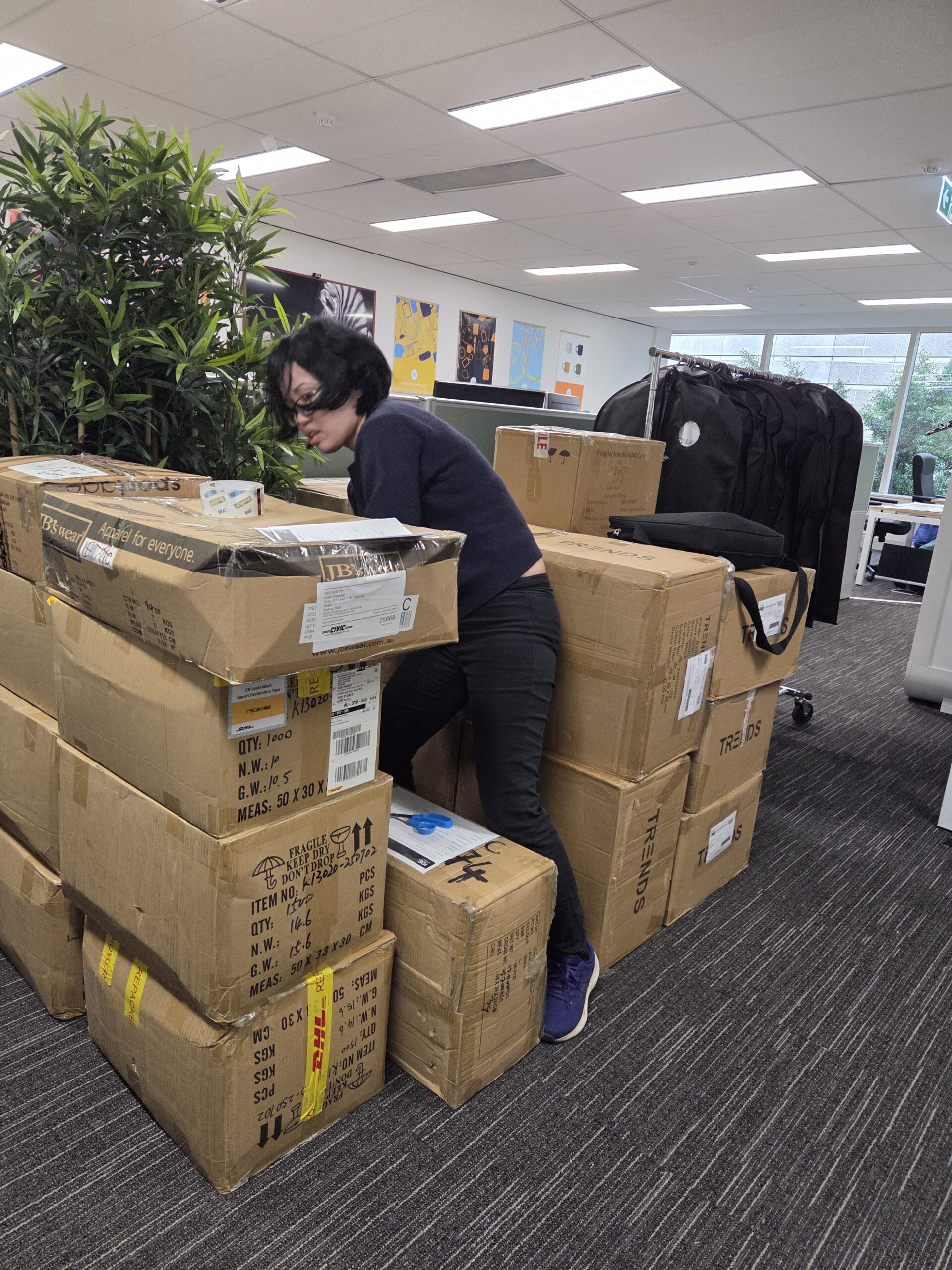 Person crouching and leaning on boxes at an office, preparing for the Australasian Gaming Expo.