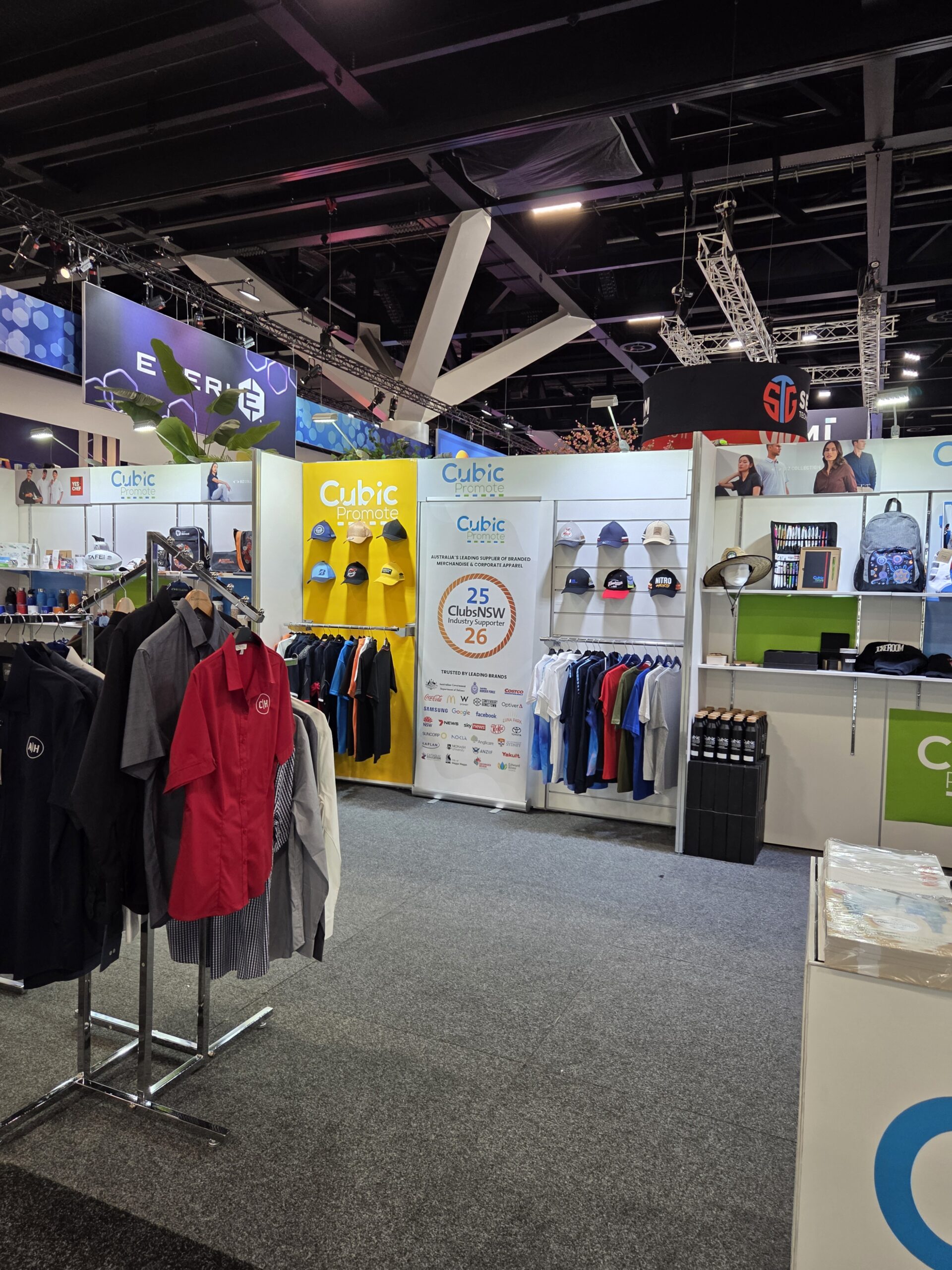 Trade show booth at the Australasian Gaming Expo with shirts, hats, and promo items on display.