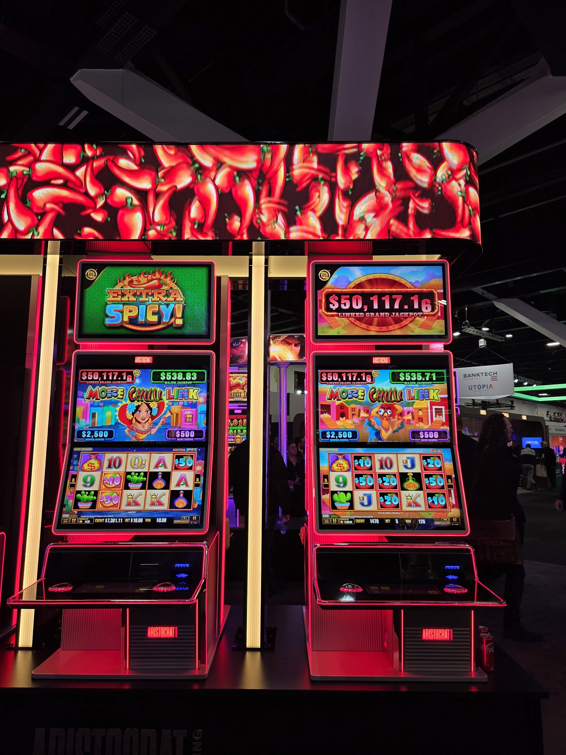 Two brightly lit slot machines with chili pepper graphics at the 2025 Australian Gaming Expo.