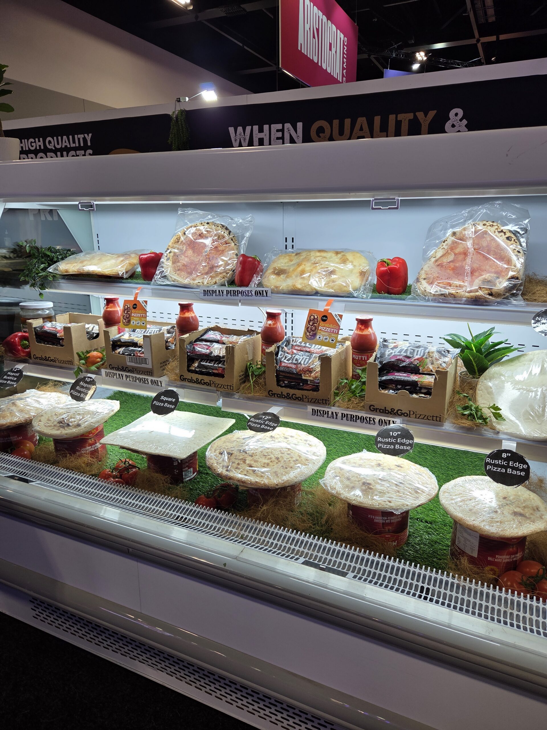 Day 1: Deli display with meats, pizzas, and veggies on artificial grass at the 2025 Expo.