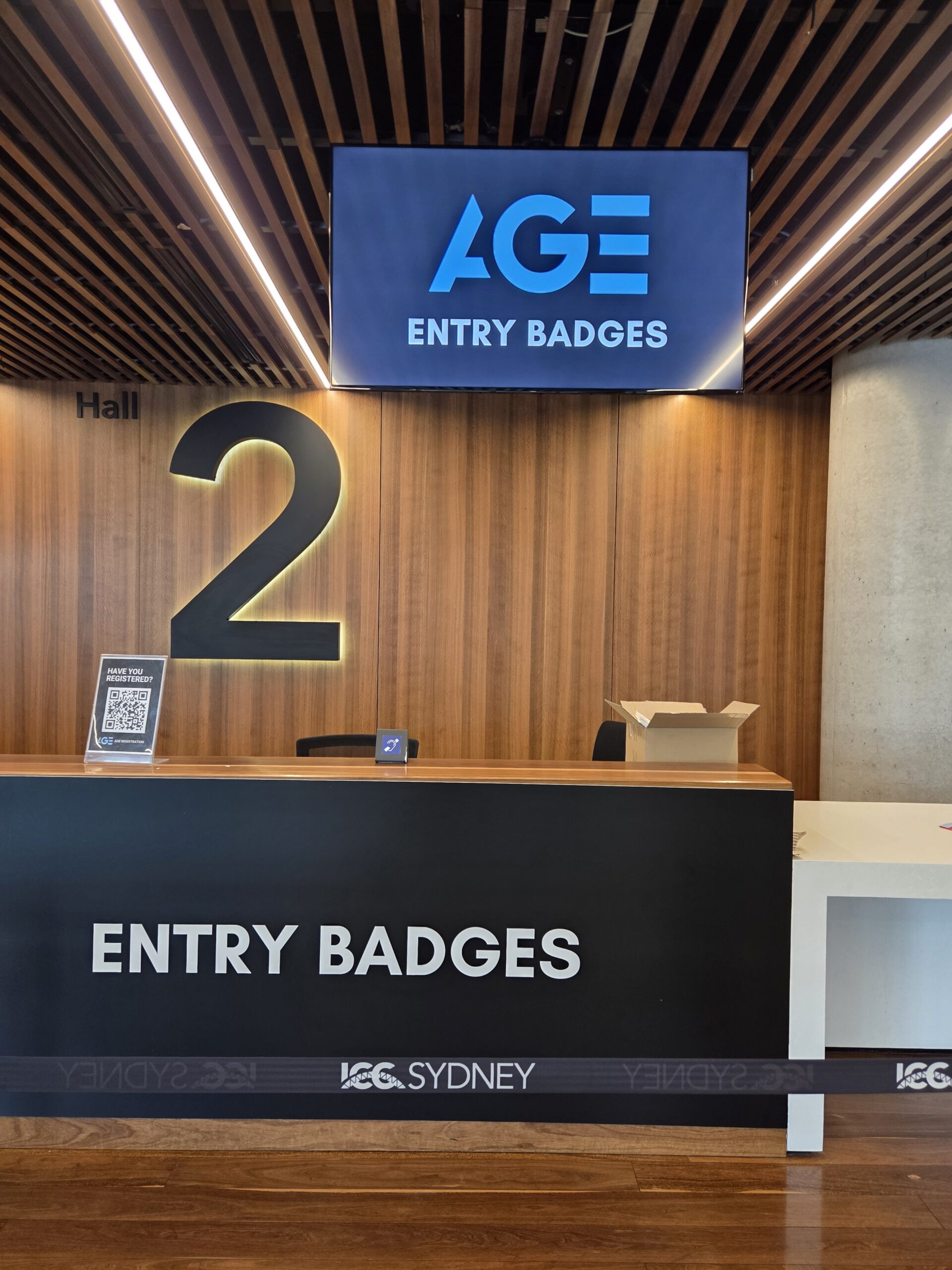 Reception desk with ENTRY BADGES sign and gaming 2025 display at ICC Sydney.