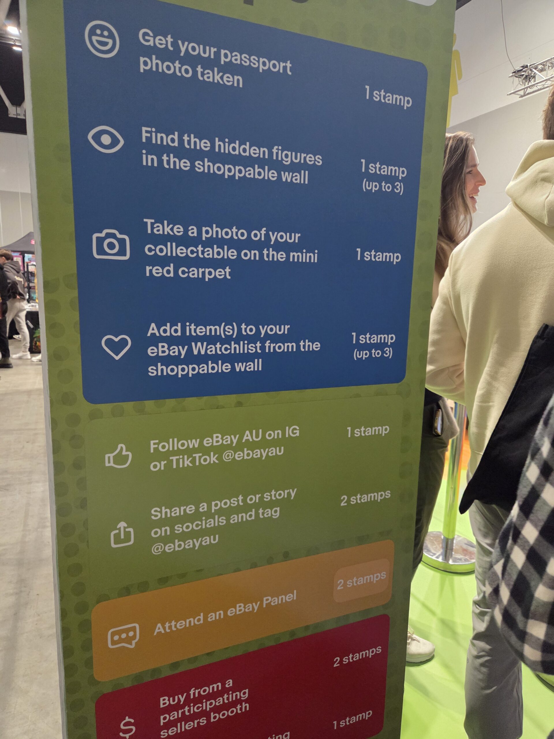 Colorful sign at Collectfest Sydney 2025 lists ways to earn stamps for custom-branded merchandise.