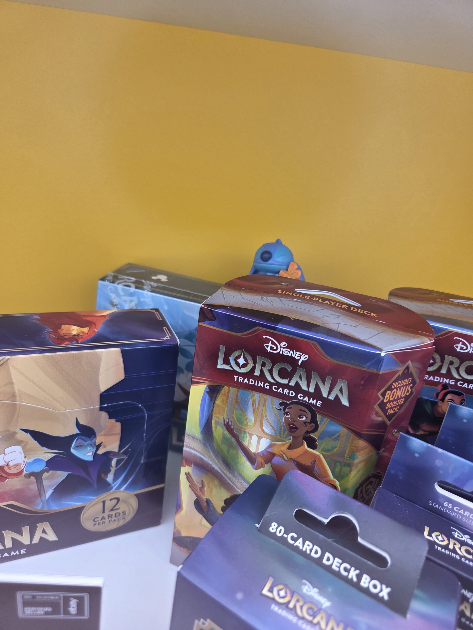Disney Lorcana trading card boxes displayed on a yellow background at Collectfest Sydney 2025.