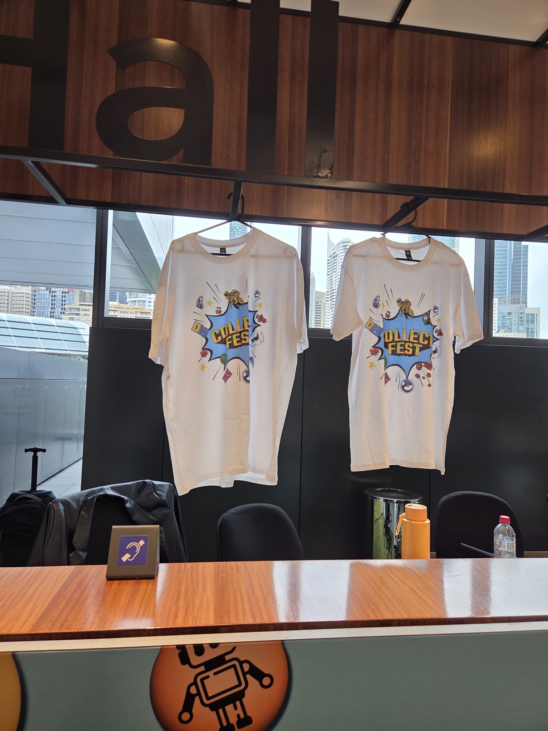 Two white Quick Fest tees with a robot graphic and water bottles at Collectfest Sydney 2025.