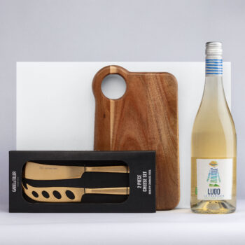 The Classic Pairing: cheese board, knives set, and white wine displayed together.