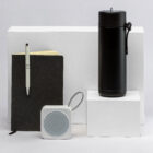 The Corporate Setup Hampers: notebook with pen, portable speaker, and black thermos.