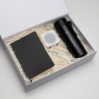 The Corporate Setup Hampers: Includes black notebook, pen, tumbler & white speaker on paper.