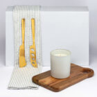 Gold cheese knives on a striped towel, perfect for displaying The Business Graze Sets.