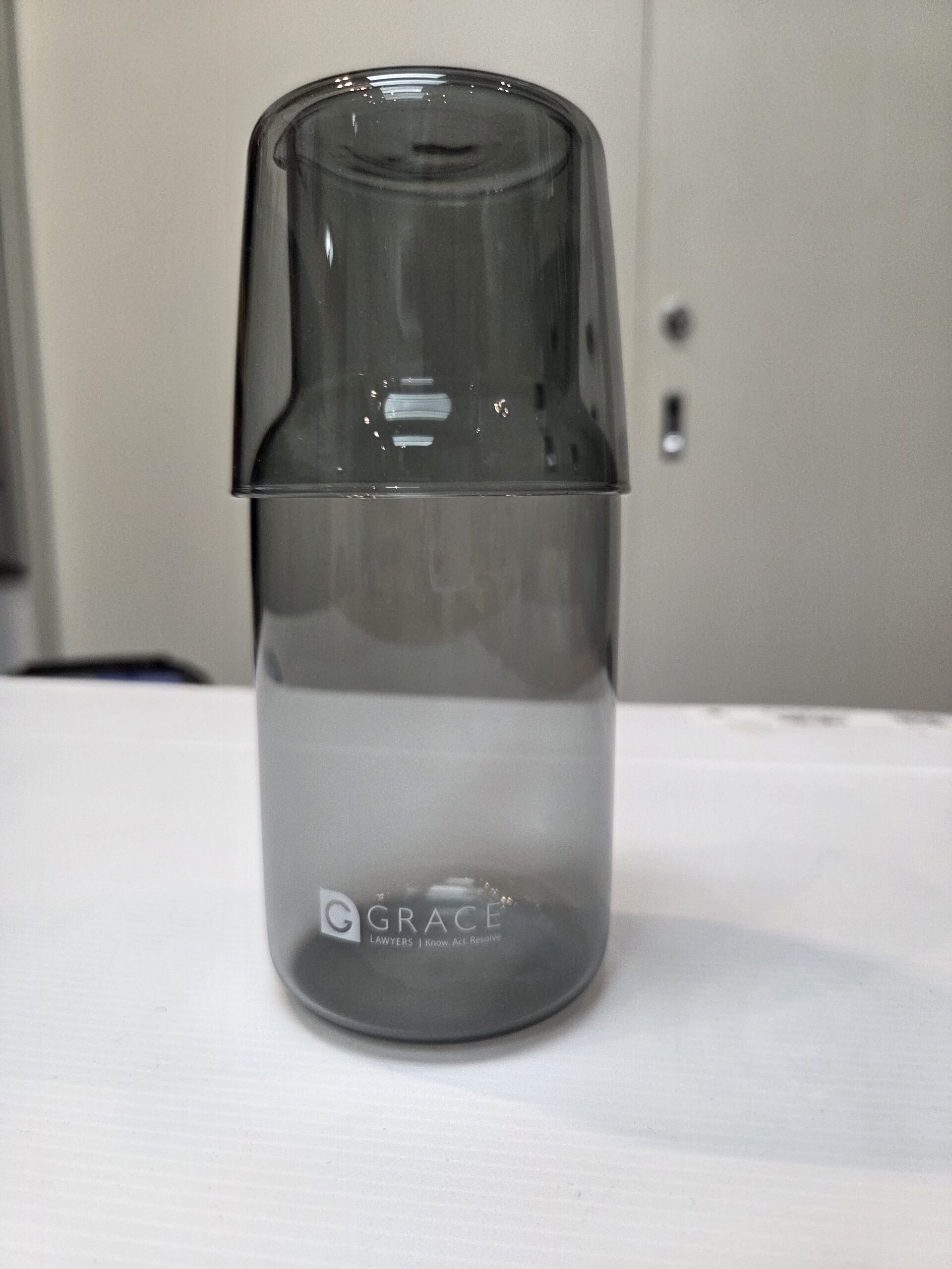 A gray glass cup is placed upside down on a tumbler labeled GRACE for Small & Medium Businesses.