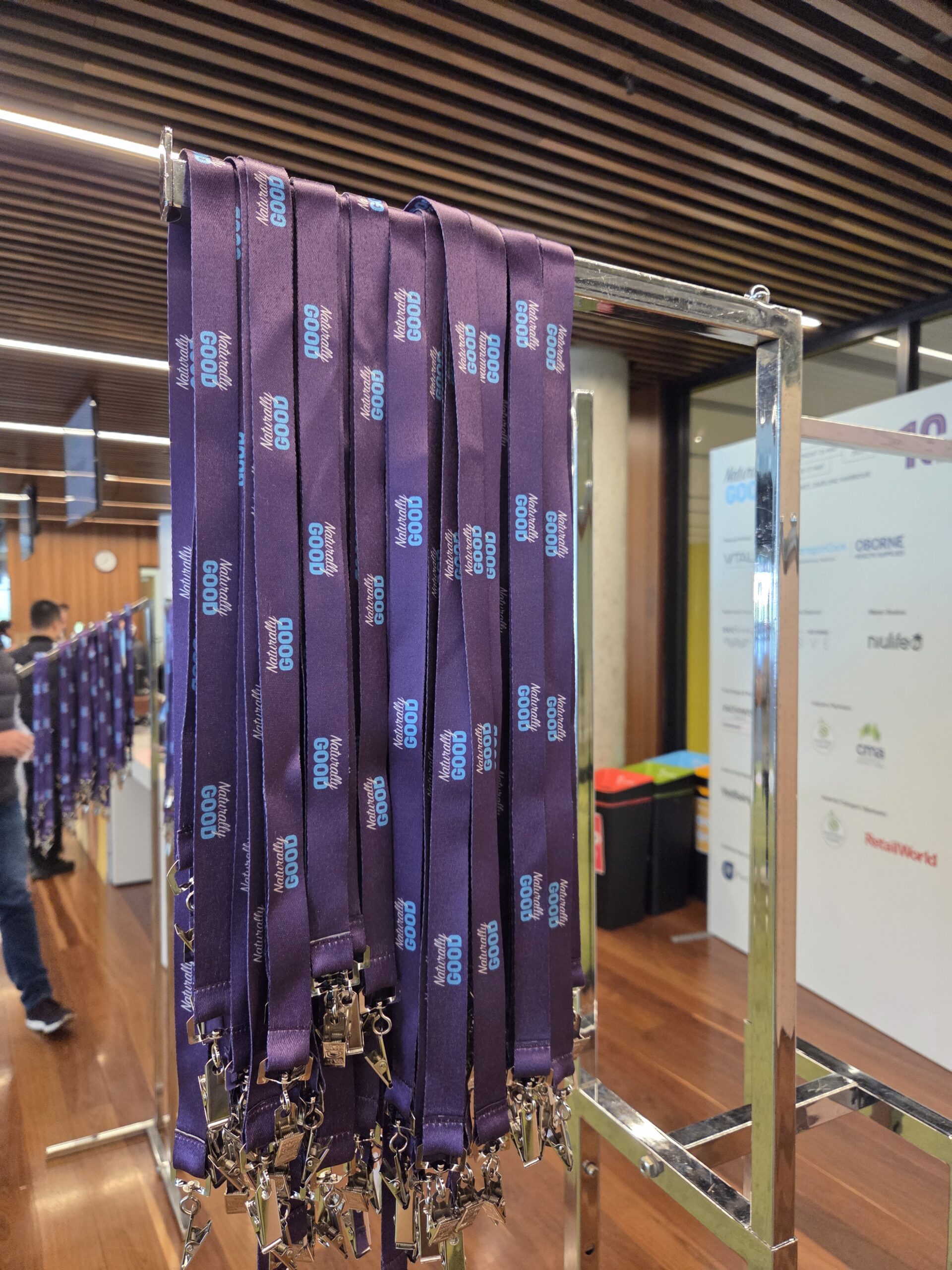 Purple event lanyards with crisp text hang on a metal rack at the tradeshow venue.