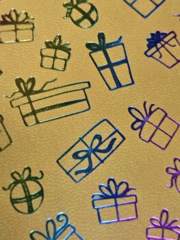 Colorful, metallic outlines of gift boxes and ornaments adorn branding notebooks on gold.