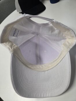 White cap turned inside out on a table, with another dark cap in the background.